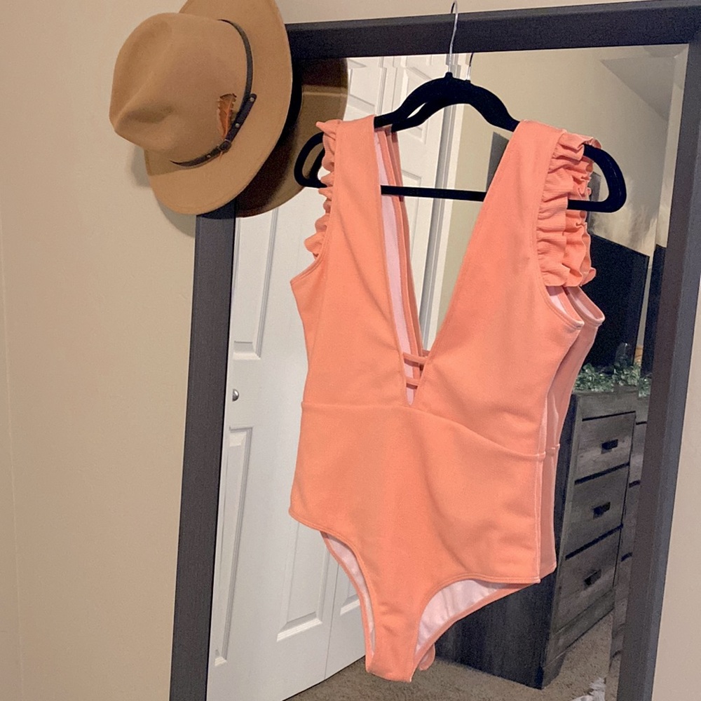 One piece swimsuit. Ruffle shoulders, deep V neckline. Removable padding.